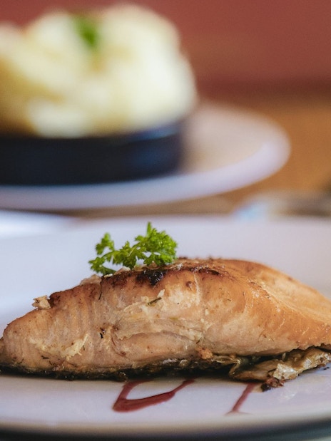 Cooked salmon fillet with mashed potatoes on a white plate.
