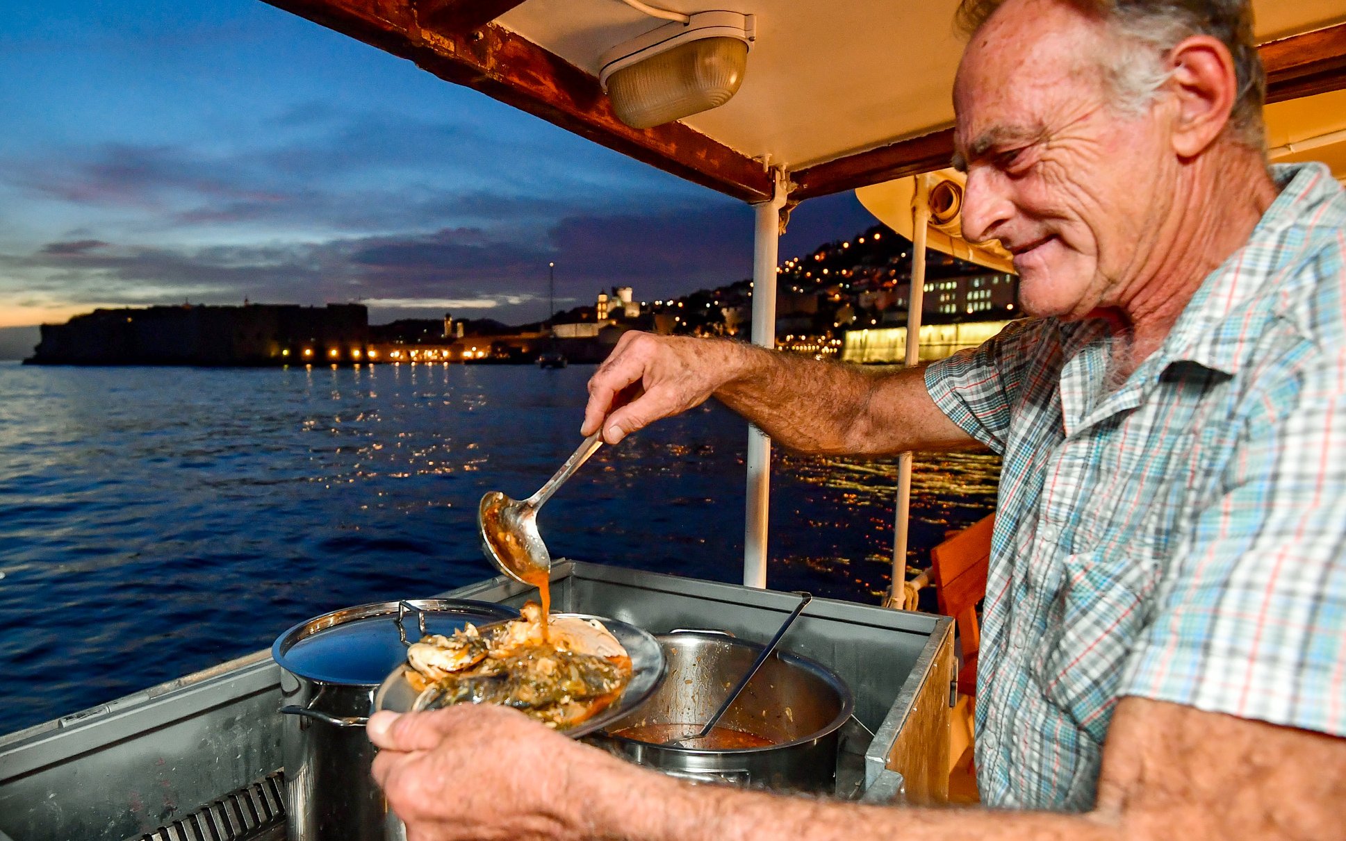 Serving seafood stew on a boat at sunset in Dubrovnik.