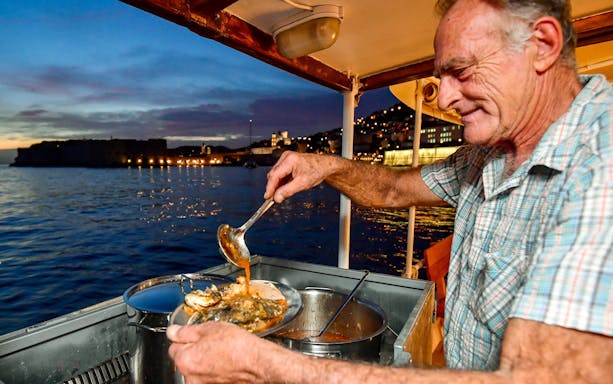 Serving seafood stew on a boat at sunset in Dubrovnik.