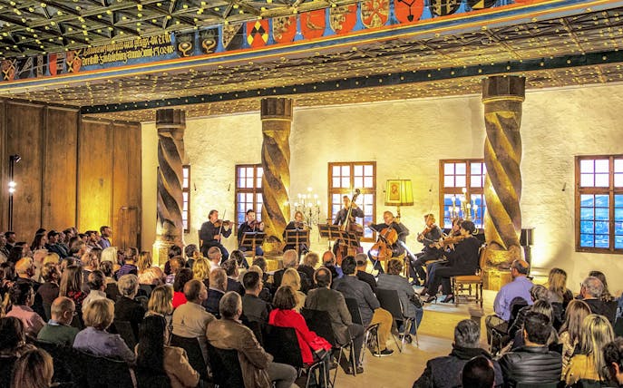 Orchestra performing at Fortress Hohensalzburg concert hall with audience seated.
