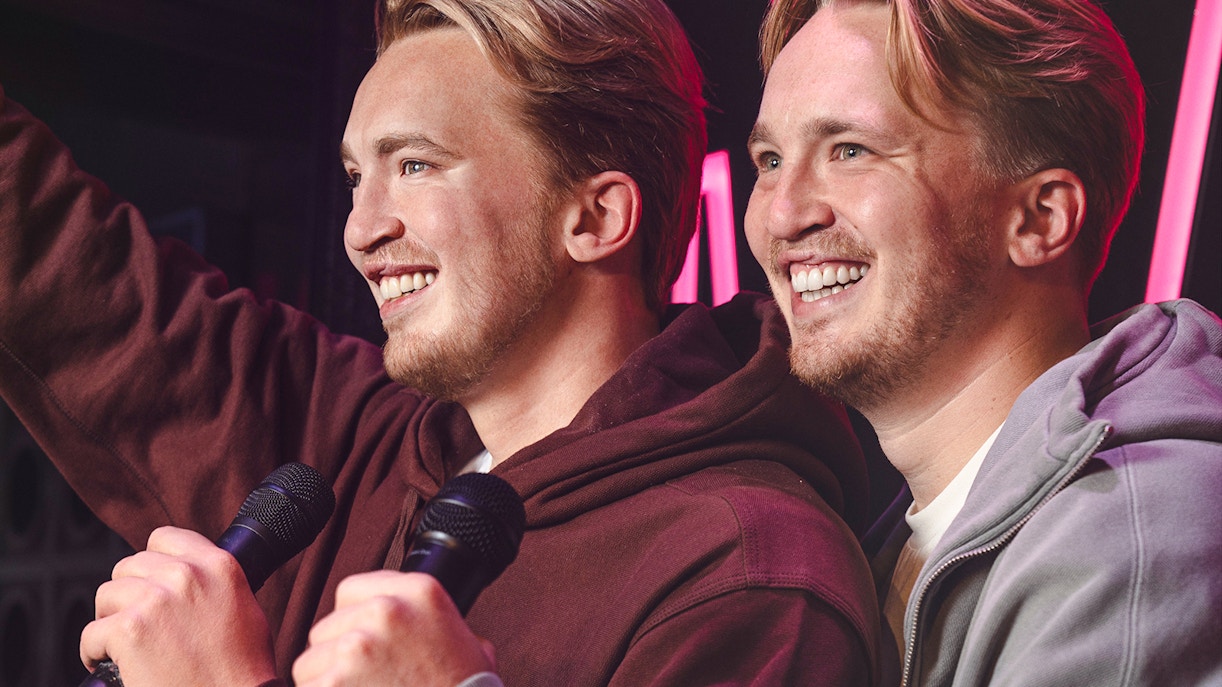 Two figures holding microphones at Madame Tussauds Amsterdam.