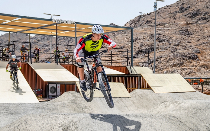 Cyclist jumping on dirt track at Fujairah Adventure Park.