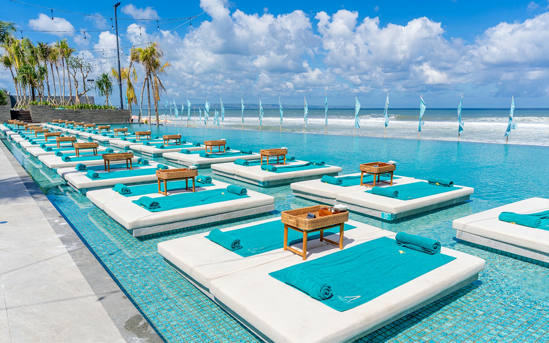 Atlas Beach Club beachfront view with sun loungers and umbrellas, Bali, Indonesia.