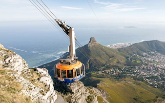 Cable car ascending Table Mountain with Cape Town and ocean view.