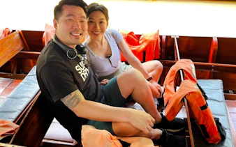 Couple sitting in a boat with life jackets during Floating Market tour from Laem Chabang, Pattaya.