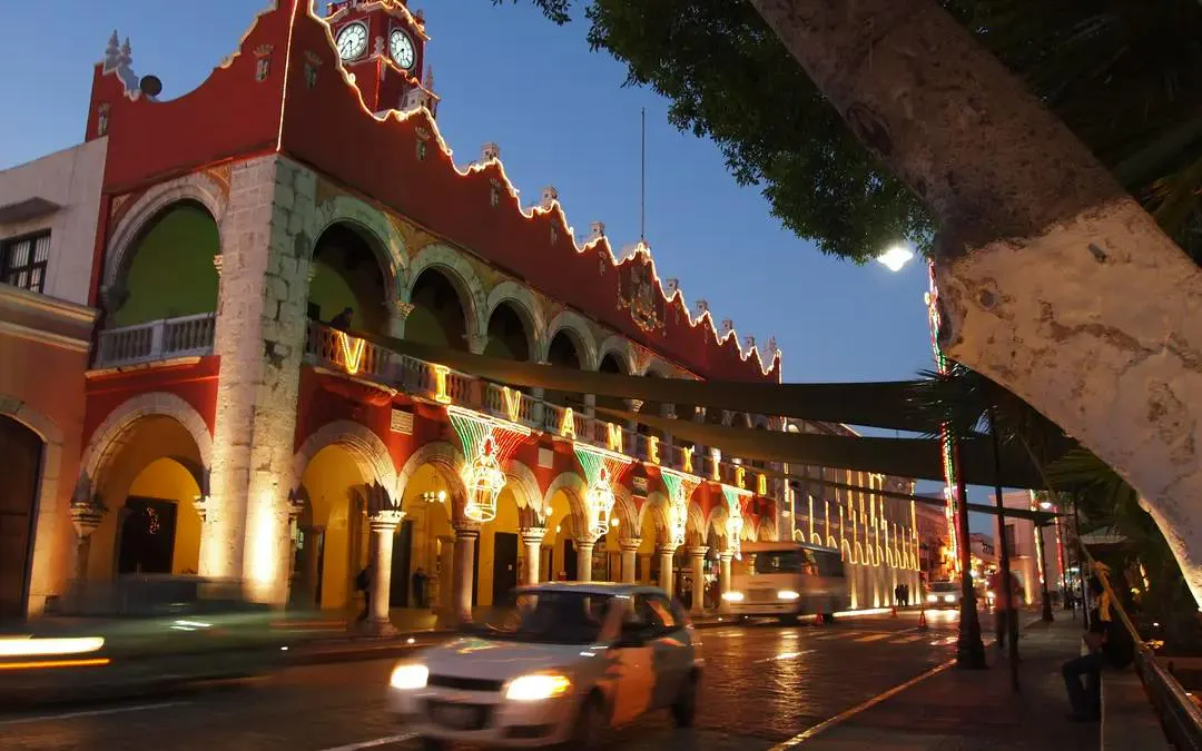 Historic Mérida city hall illuminated at night, part of The Ghost of T'Hó exploration game.