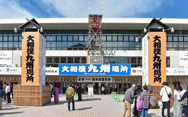 Fukuoka Sumo Tournament entrance with visitors gathering outside the arena.