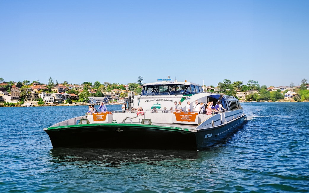 Ferry on Sydney Harbour with passengers, cityscape in background, part of Blue Mountains tour.