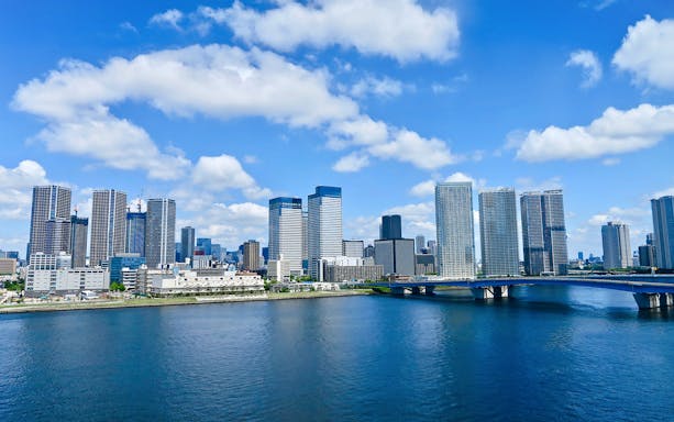 Skyline of Toyosu area in Tokyo Bay with high-rise buildings and a bridge over the water.
