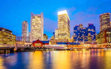 Boston skyline at dusk viewed from a sunset cruise on the harbor.
