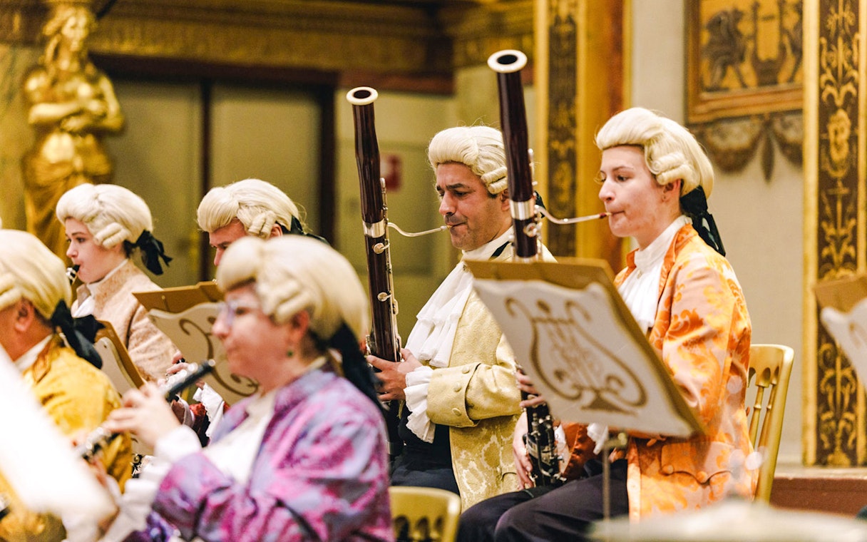 Musicians in period costumes playing woodwind instruments at Vienna's Musikverein Golden Hall.