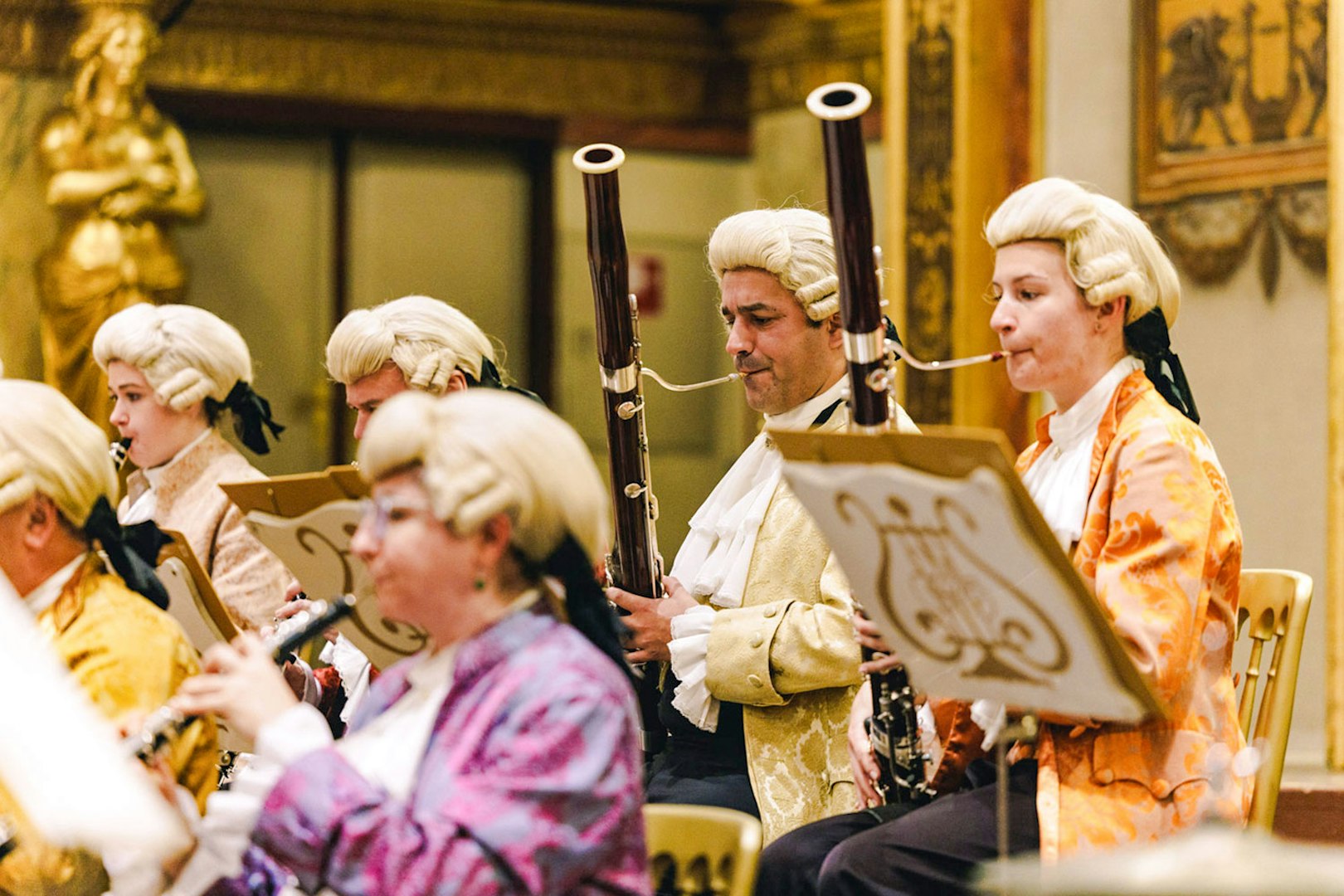 Musicians in period costumes playing woodwind instruments at Vienna's Musikverein Golden Hall.