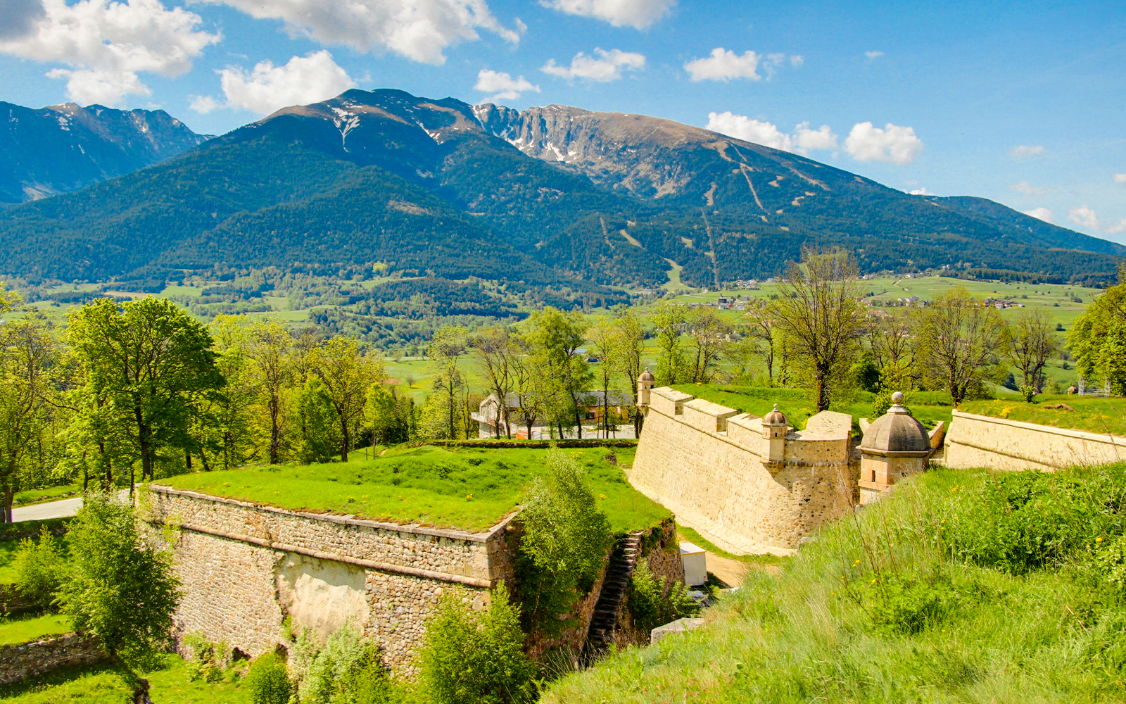 Forteresse de Montlouis with lush greenery and mountain backdrop in France.