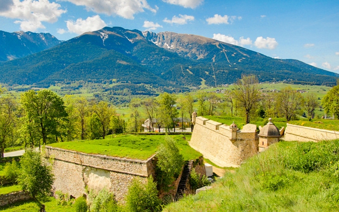 Forteresse de Montlouis with lush greenery and mountain backdrop in France.
