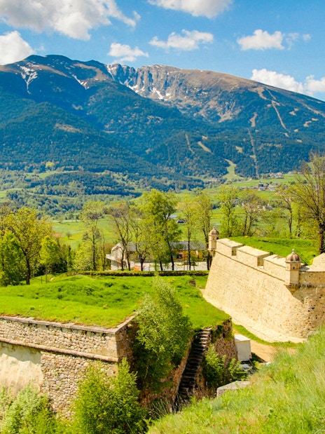 Forteresse de Montlouis with lush greenery and mountain backdrop in France.