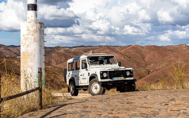 Jeep on a scenic trail in Algarve with rolling hills in the background.