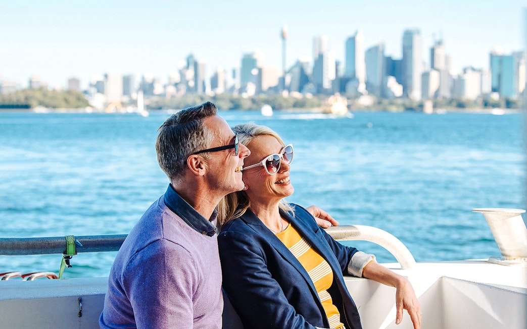 Couple enjoying a whale watching tour on Sydney Harbour with city skyline in the background.