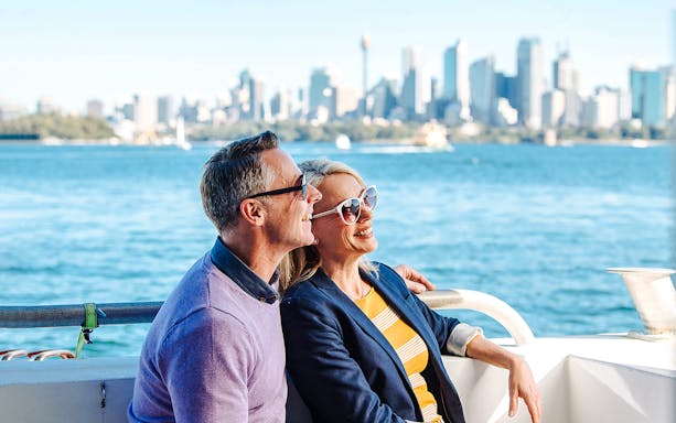 Couple enjoying a whale watching tour on Sydney Harbour with city skyline in the background.