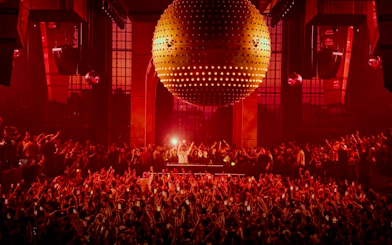Crowd enjoying a DJ performance under a large disco ball at Paradise, Ibiza.