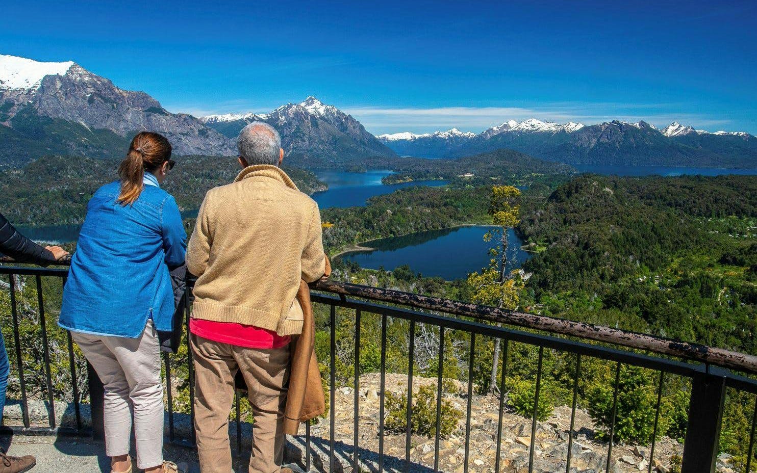Visitors enjoying panoramic views from Mount Campanario summit, overlooking lakes and mountains.
