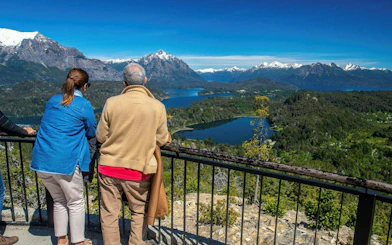 Visitors enjoying panoramic views from Mount Campanario summit, overlooking lakes and mountains.