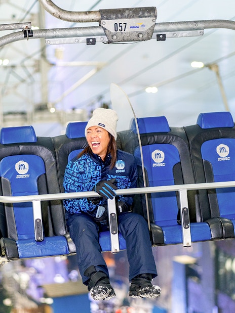 Chairlift ride at Ski Dubai Snow Park with people enjoying the view.