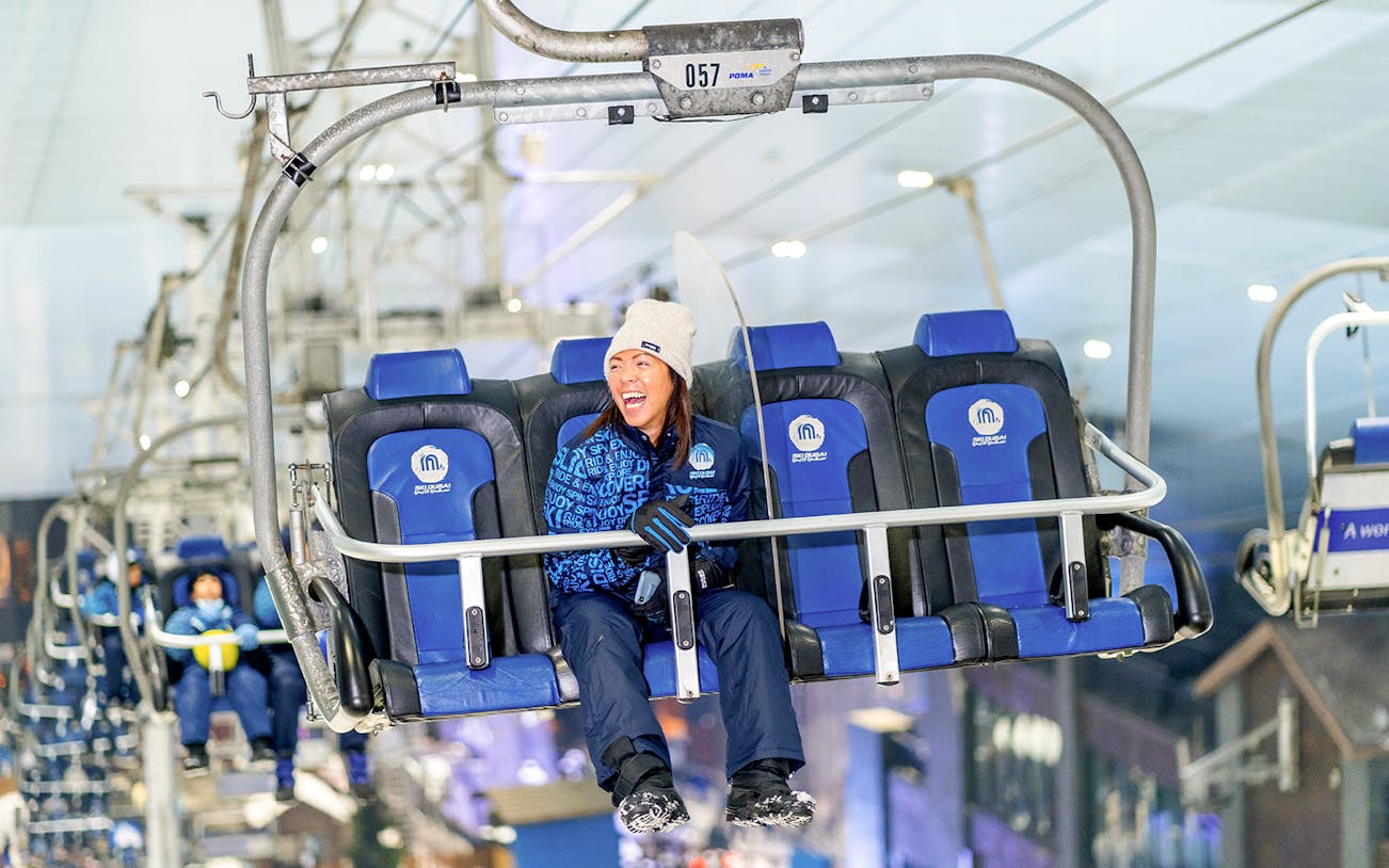 Chairlift ride at Ski Dubai Snow Park with people enjoying the view.