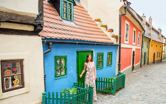 Colorful houses on Prague's Golden Lane with a visitor at a blue cottage.