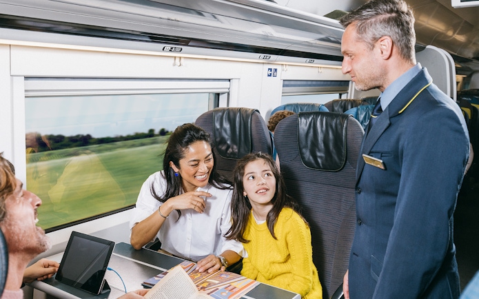 Family enjoying train journey with conductor, Interrail Germany Mobile Pass.