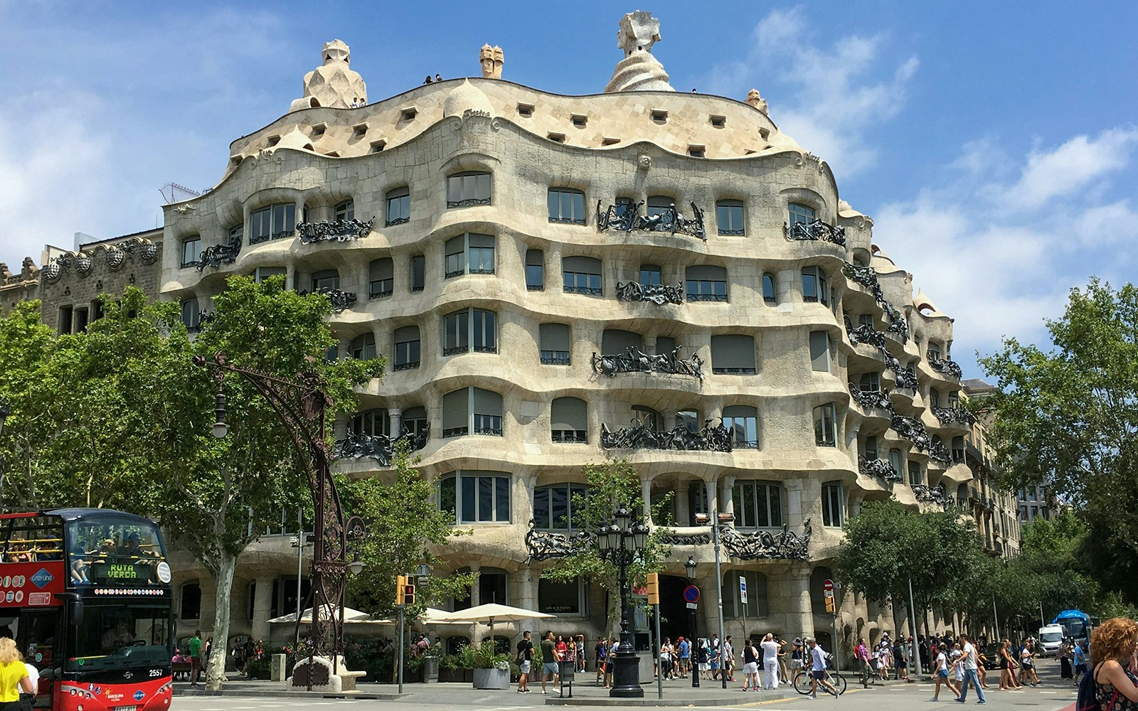 Casa Mila viewed from across the street, Barcelona, with tourists and a tour bus.