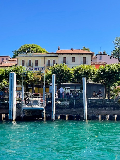 Isola Bella dock with buildings and trees, part of the Hop-on Hop-off Isole Borromee tour.
