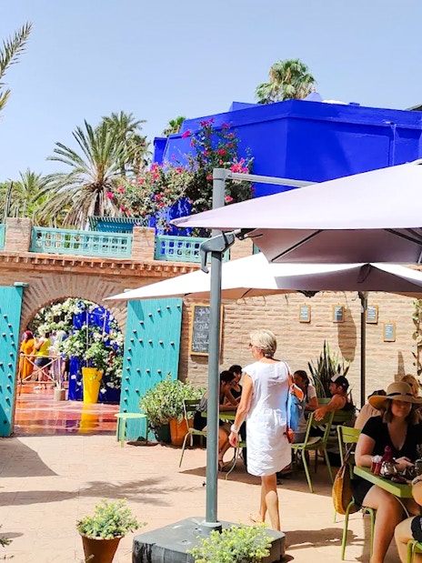Jardin Majorelle entrance with visitors, blue building, and garden seating area in Marrakech.