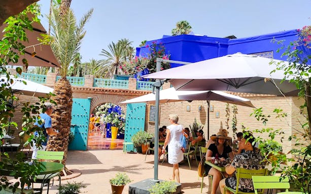 Jardin Majorelle entrance with visitors, blue building, and garden seating area in Marrakech.
