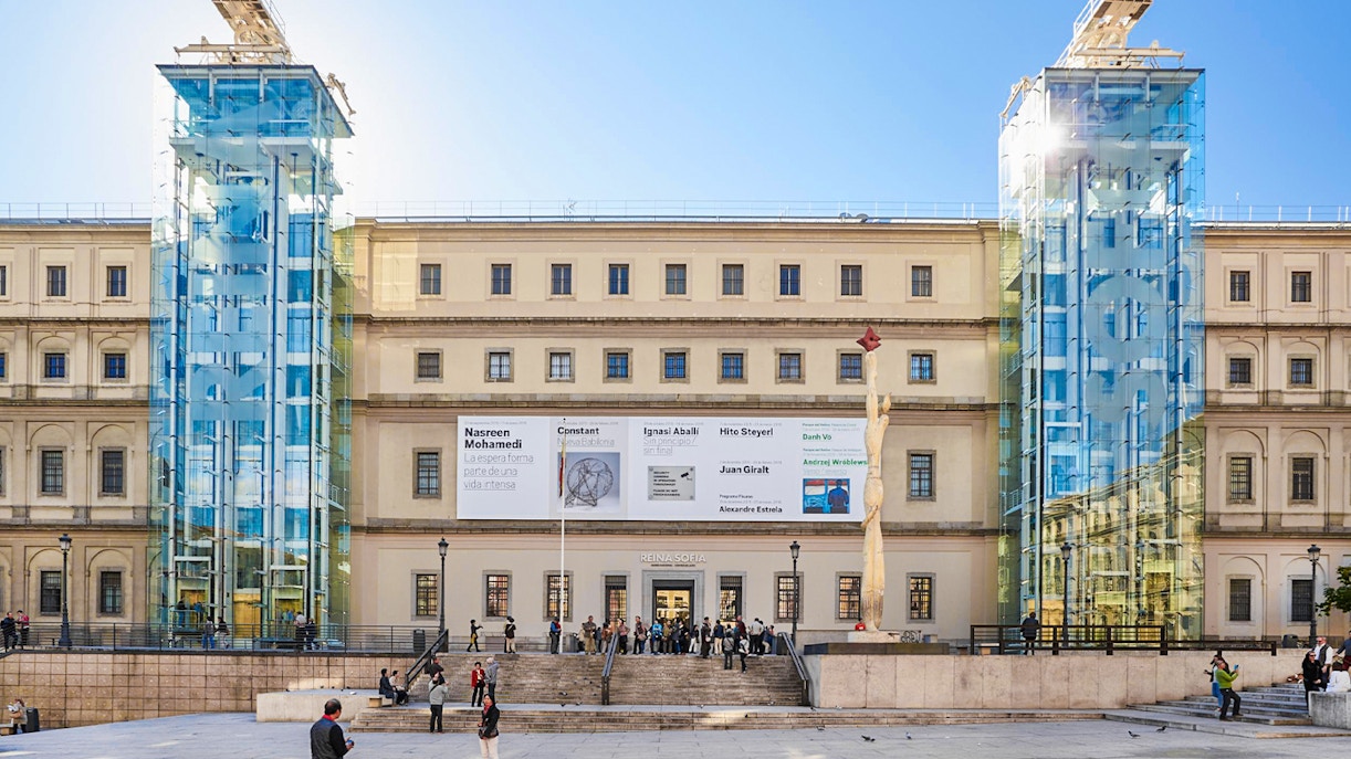 Reina Sofia Museum entrance with glass elevators and visitors in Madrid.