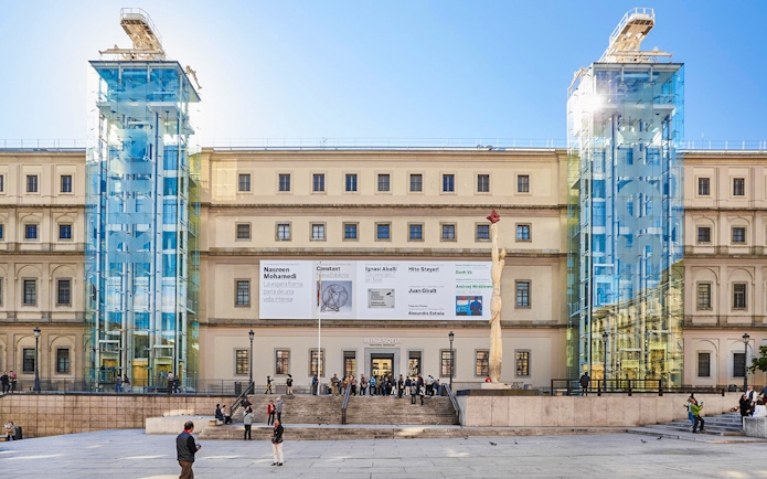 Reina Sofia Museum entrance with glass elevators and visitors in Madrid.