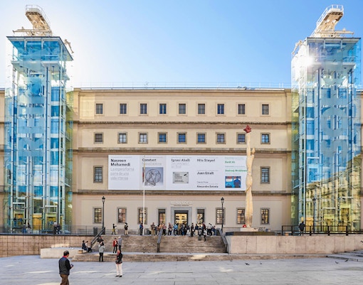 Reina Sofia Museum entrance with glass elevators and visitors in Madrid.