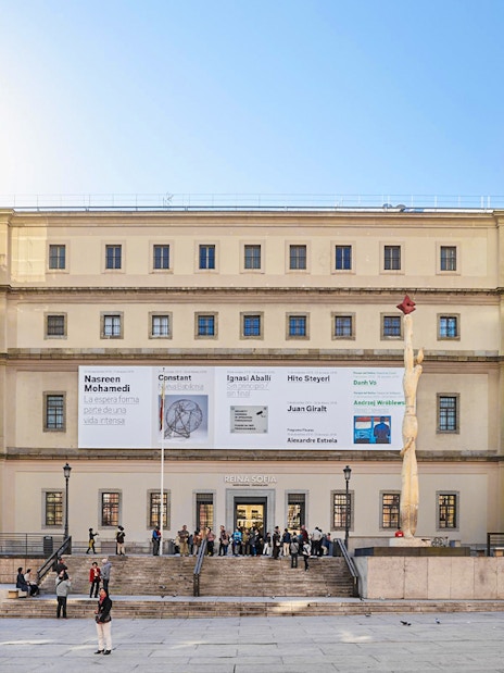 Reina Sofia Museum entrance with glass elevators and visitors in Madrid.