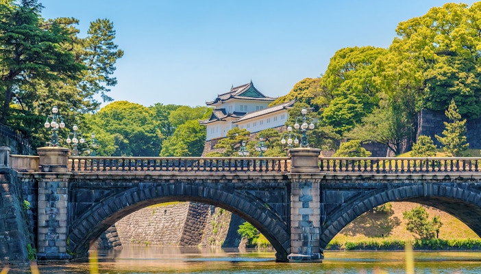 Tokyo Imperial Palace with Nijubashi Bridge in foreground, surrounded by lush greenery.