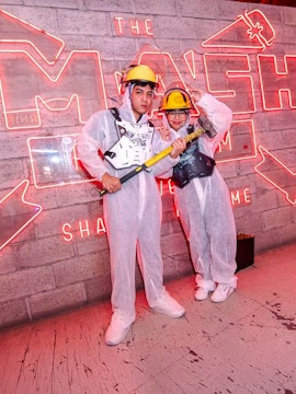 Visitors in protective gear holding sledgehammers at a Smash Room experience.