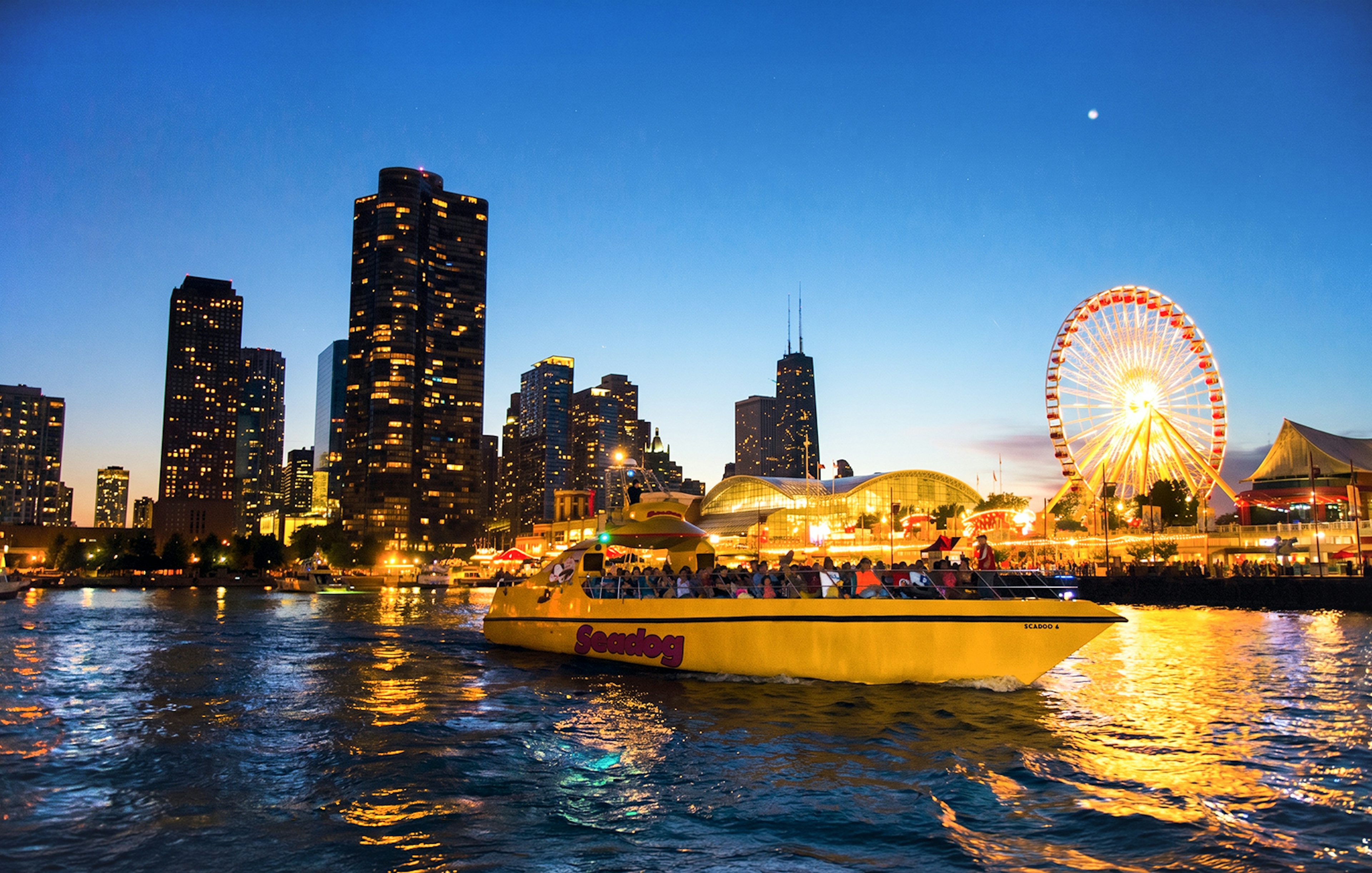 Sea Dog boat cruising on Lake Michigan with Chicago skyline and Ferris wheel at dusk.