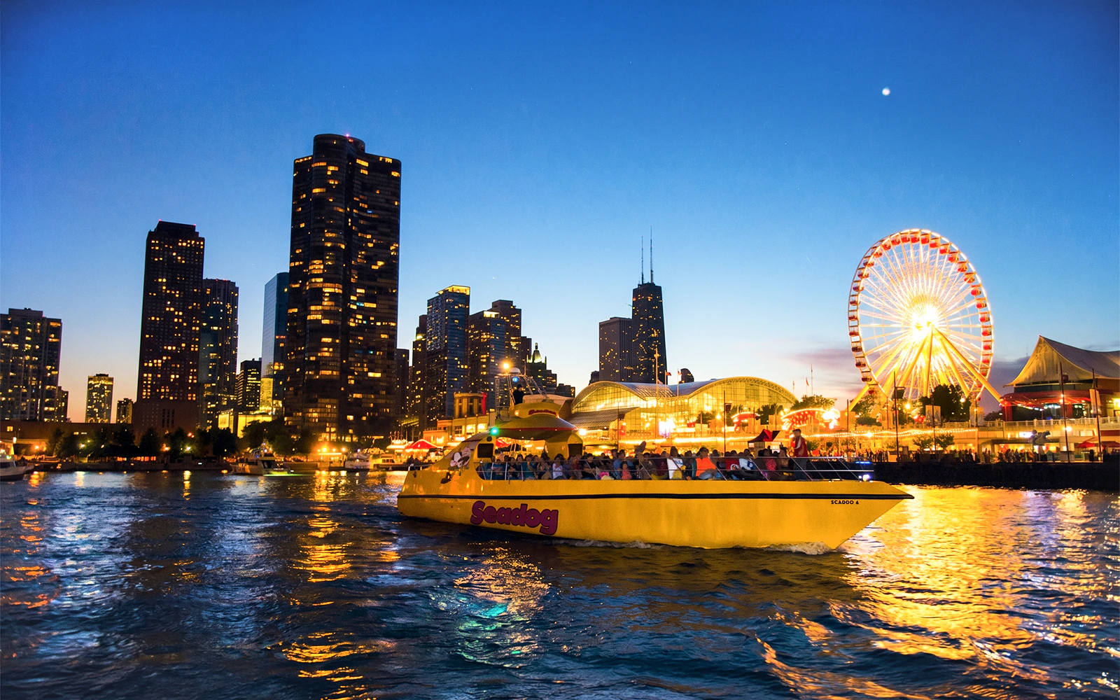Sea Dog boat cruising on Lake Michigan with Chicago skyline and Ferris wheel at dusk.