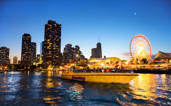 Sea Dog boat cruising on Lake Michigan with Chicago skyline and Ferris wheel at dusk.