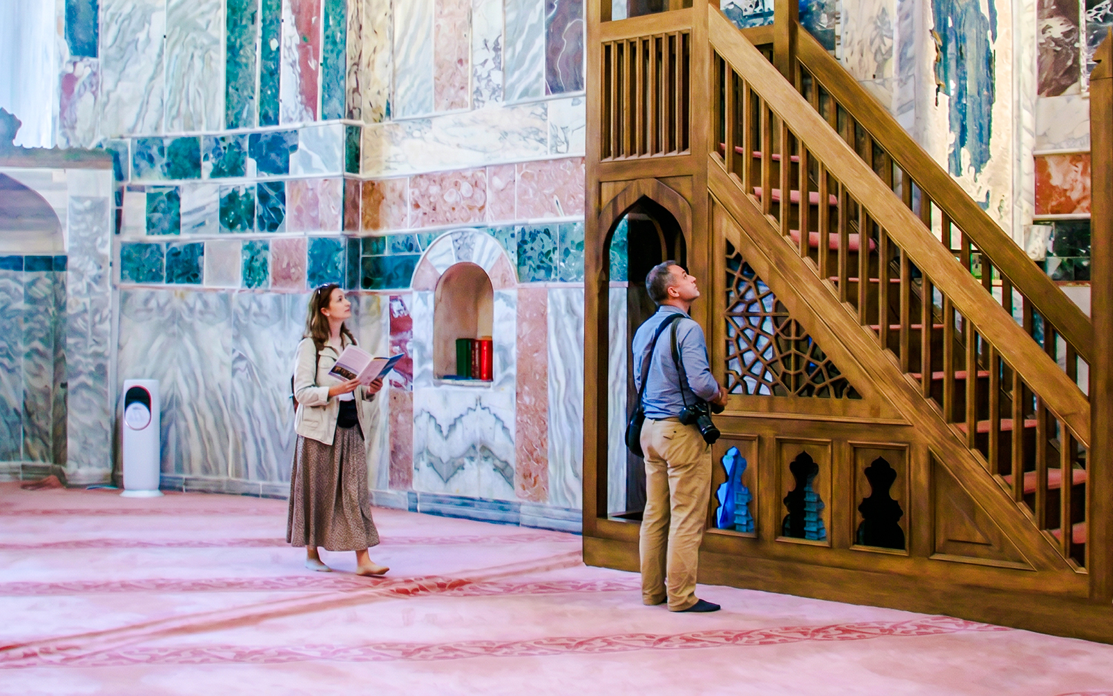 Guests exploring the interior of Kariye Mosque, Istanbul, near ornate wooden staircase.