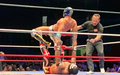 Wrestlers performing a move in Lucha Libre match at Arena Mexico.