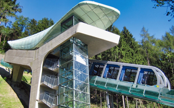 Nordkettenbahn funicular ascending through forested area in Innsbruck, Austria.