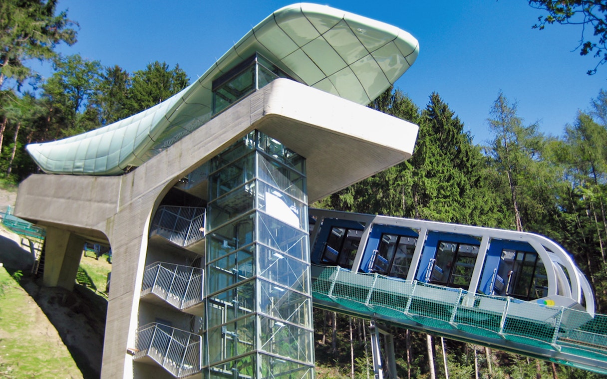 Nordkettenbahn funicular ascending through forested area in Innsbruck, Austria.