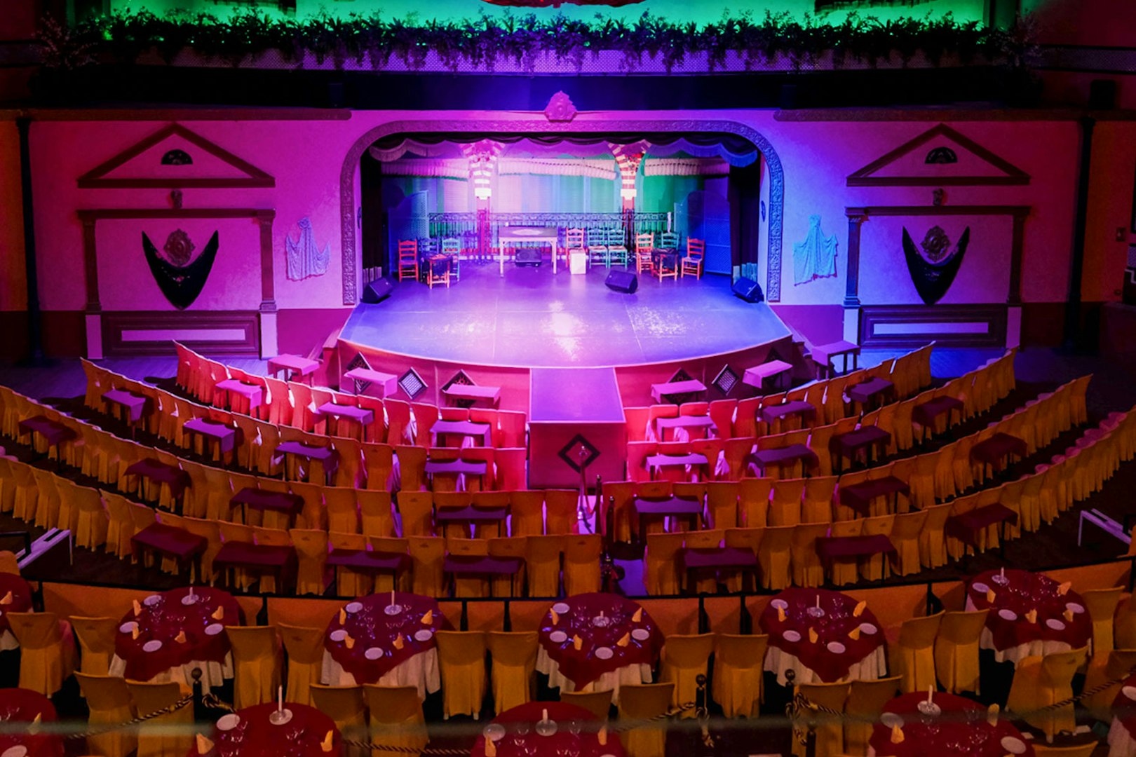 Stage setup at El Palacio Andaluz for a Flamenco show, featuring colorful seating and lighting.