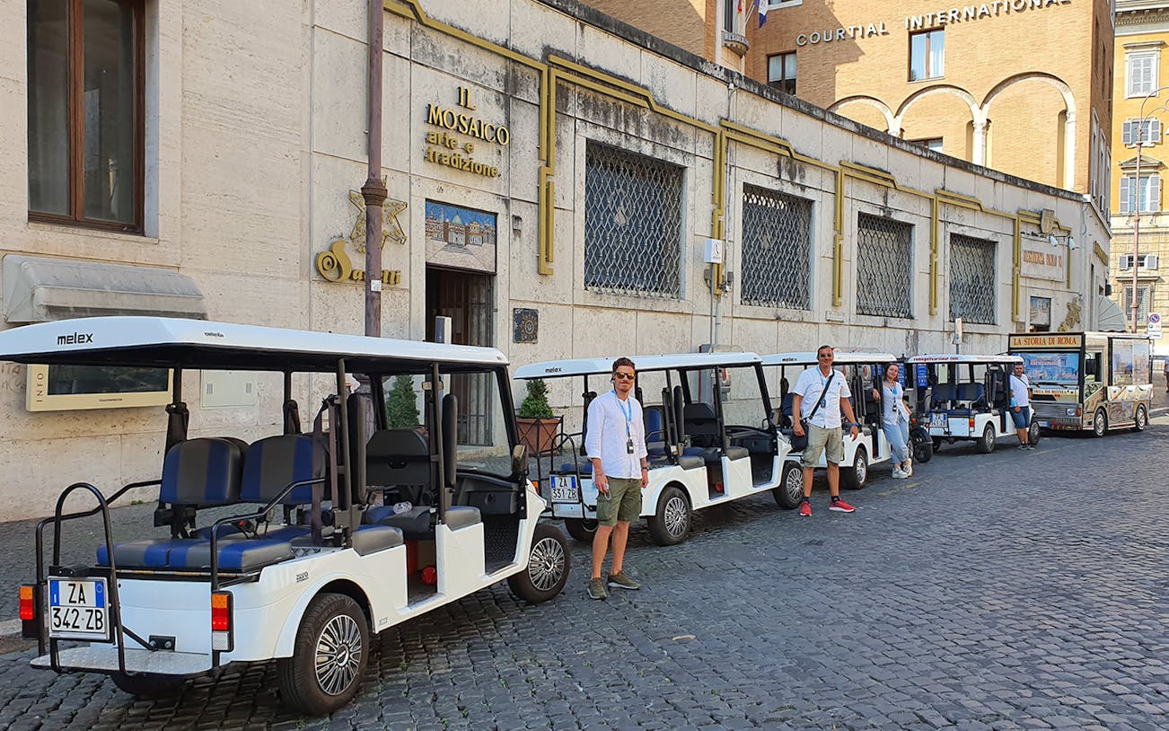 Golf carts lined up for tours in Rome, Italy, with guides standing nearby.