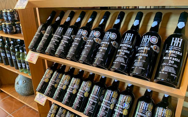 Madeira wine bottles displayed on shelves during vineyard tour.