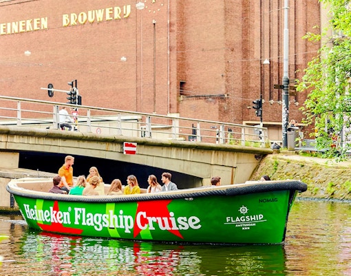 Tourists on Heineken Experience cruise boat in Amsterdam canal.